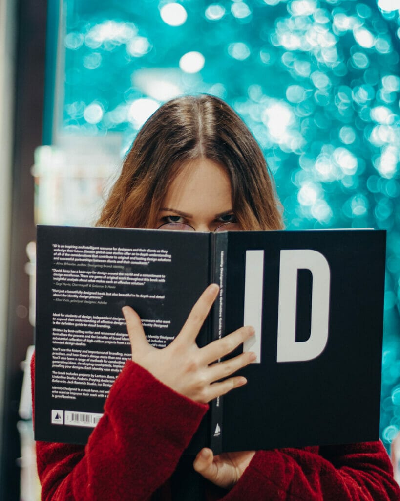 girl holding up a book in front of face