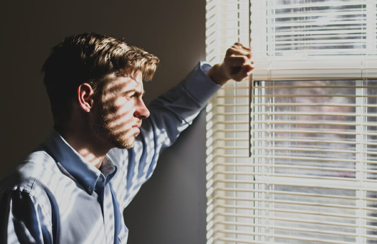 man looking out window sadly