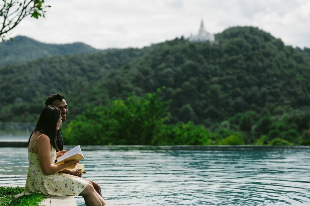 woman reading a book with legs in the water